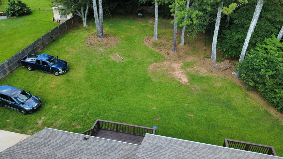 Top-down drone view of residential properties showing rooftops, lot boundaries, and yard space