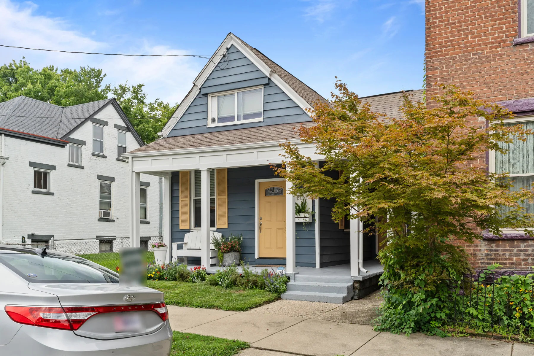 Front exterior of a renovated Cincinnati cottage with blue siding and covered porch shot by 513Shutter