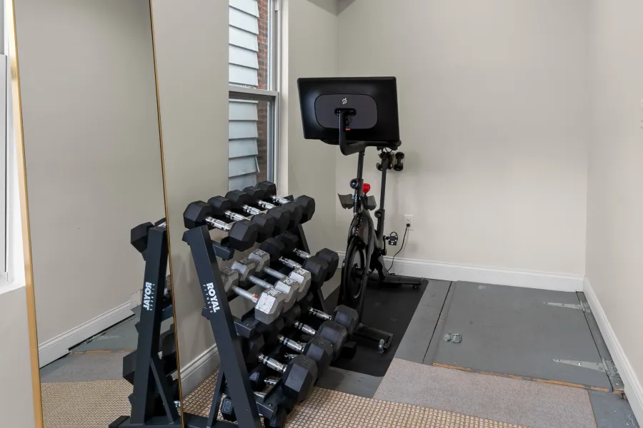Home gym area with spin bike, dumbbell rack, and rubber flooring — photographed by 513Shutter Cincinnati