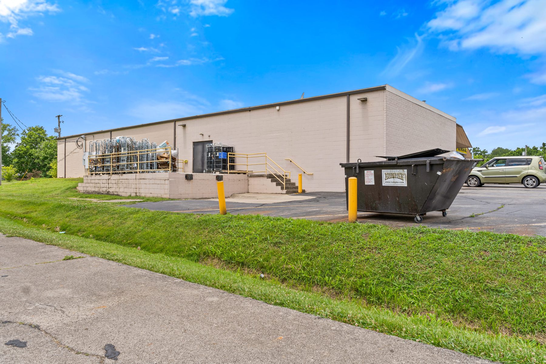 Rear exterior of the commercial building showing dumpster area and access stairs