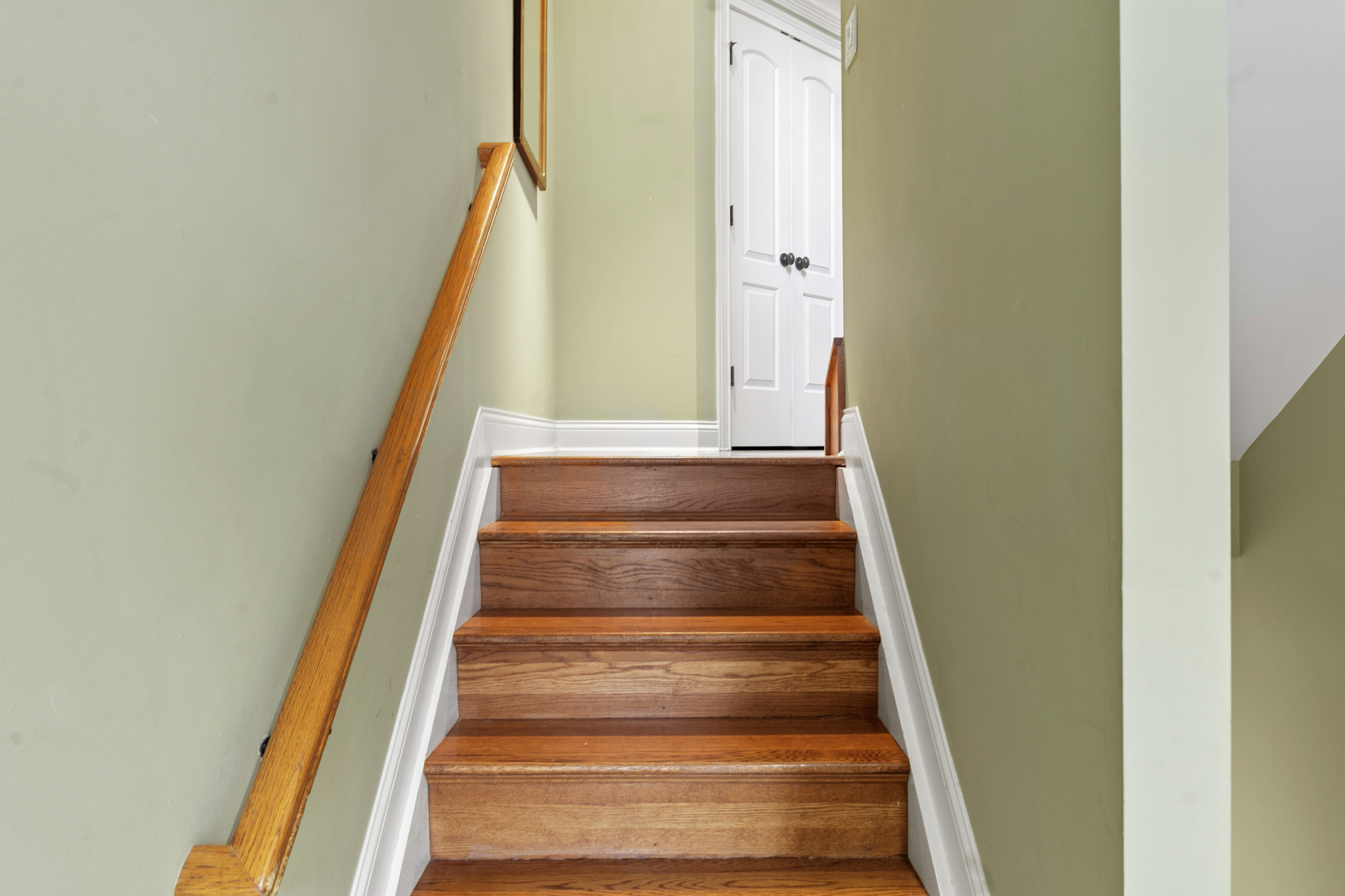 Entry-level staircase with wood treads, white risers, and oak handrail leading to upper landing