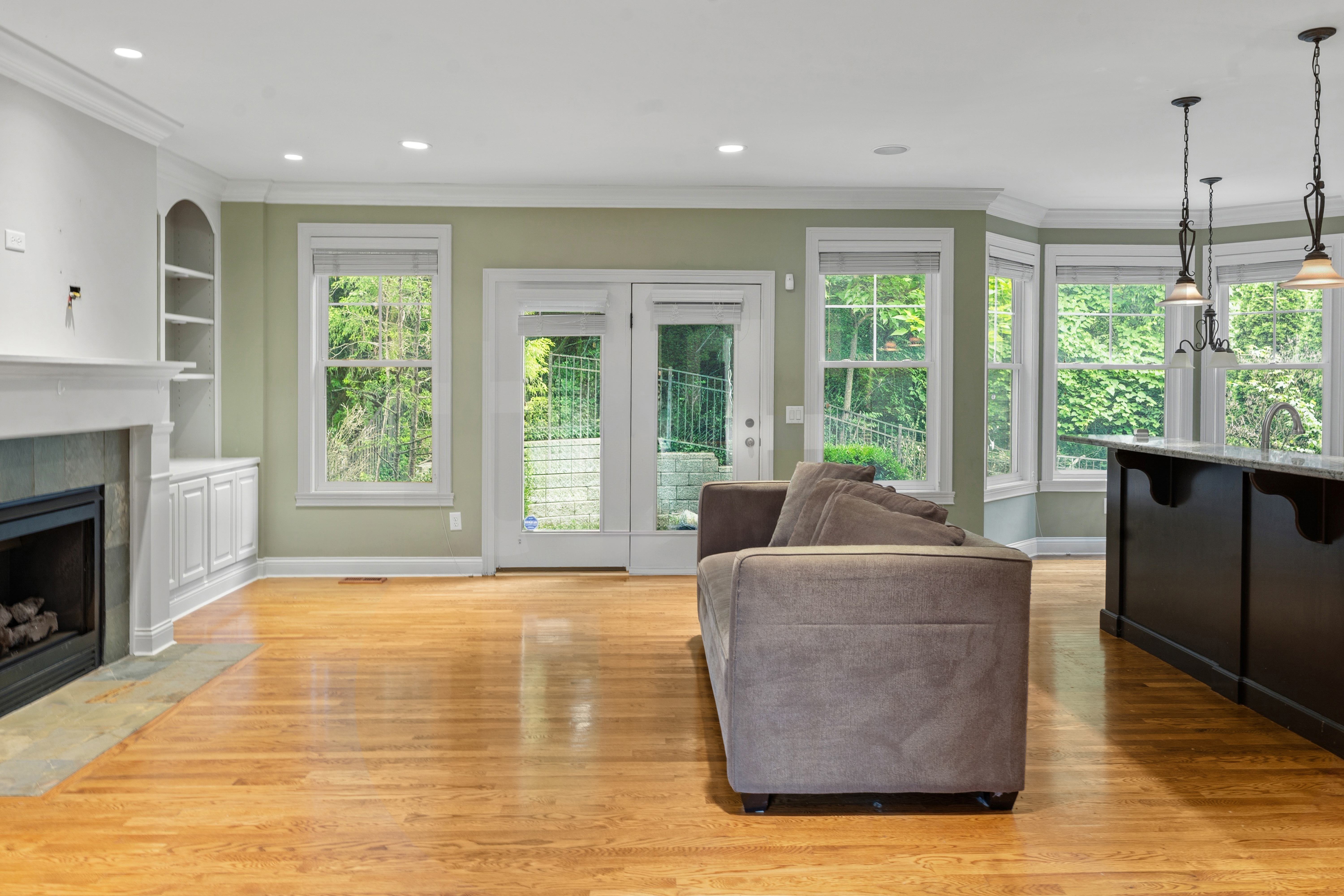 Family room with gas fireplace, hardwood floors, French doors to patio, and bay window with natural light
