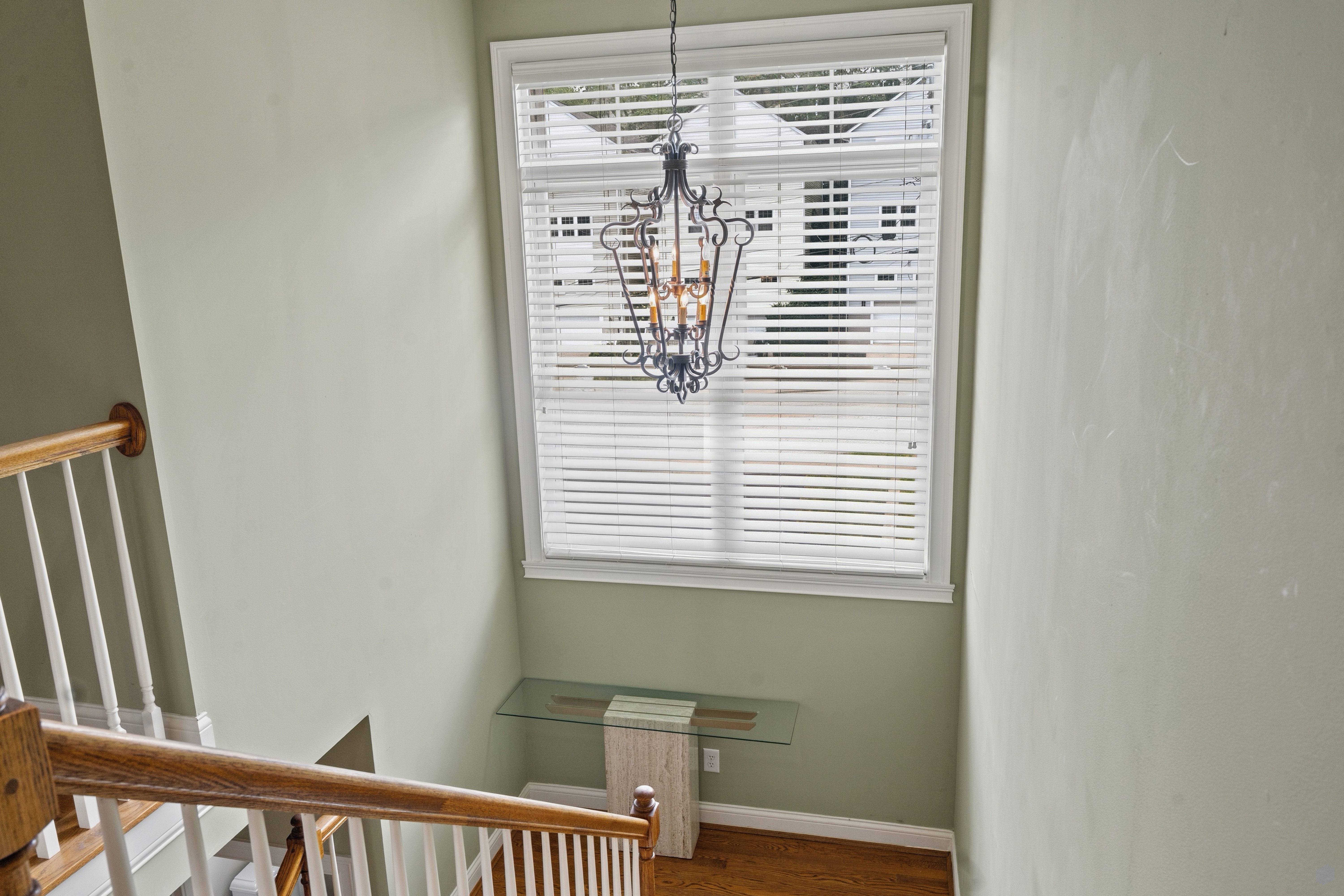 Foyer view from upper landing showing iron chandelier and glass console table below