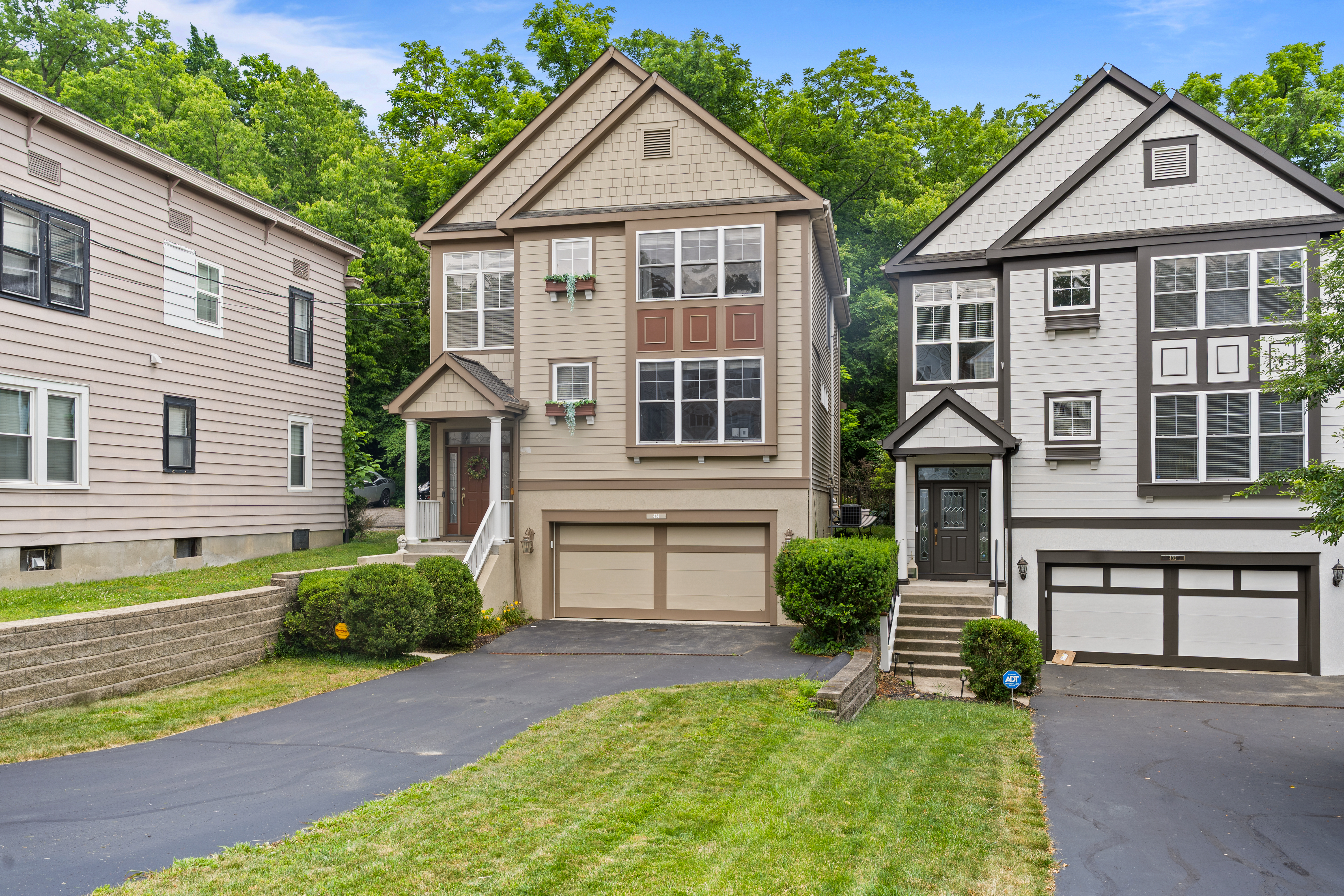 Front exterior of a three-story colonial-style home with garage and manicured landscaping