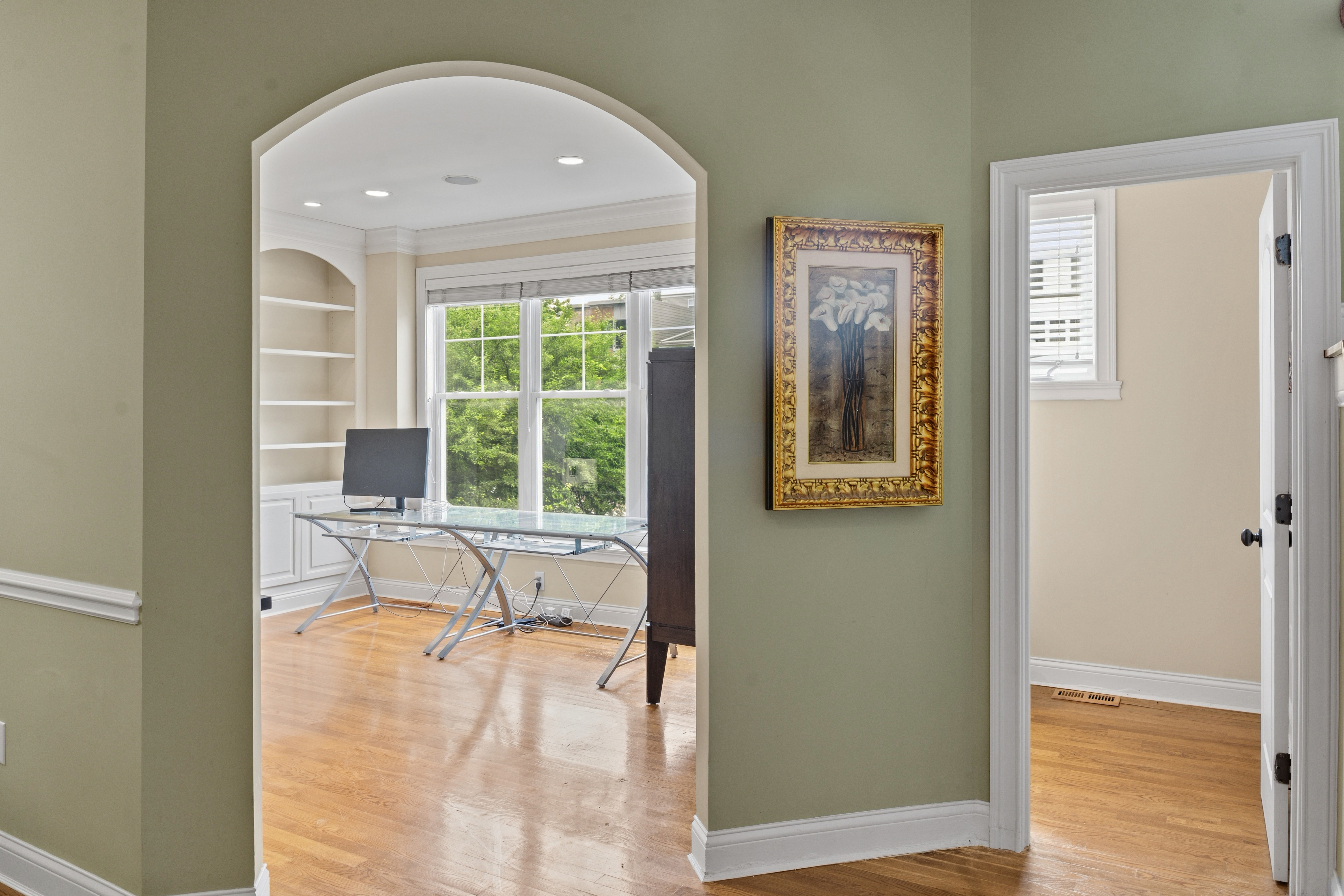 Main floor hallway with arched entryway leading into the home office and adjacent rooms