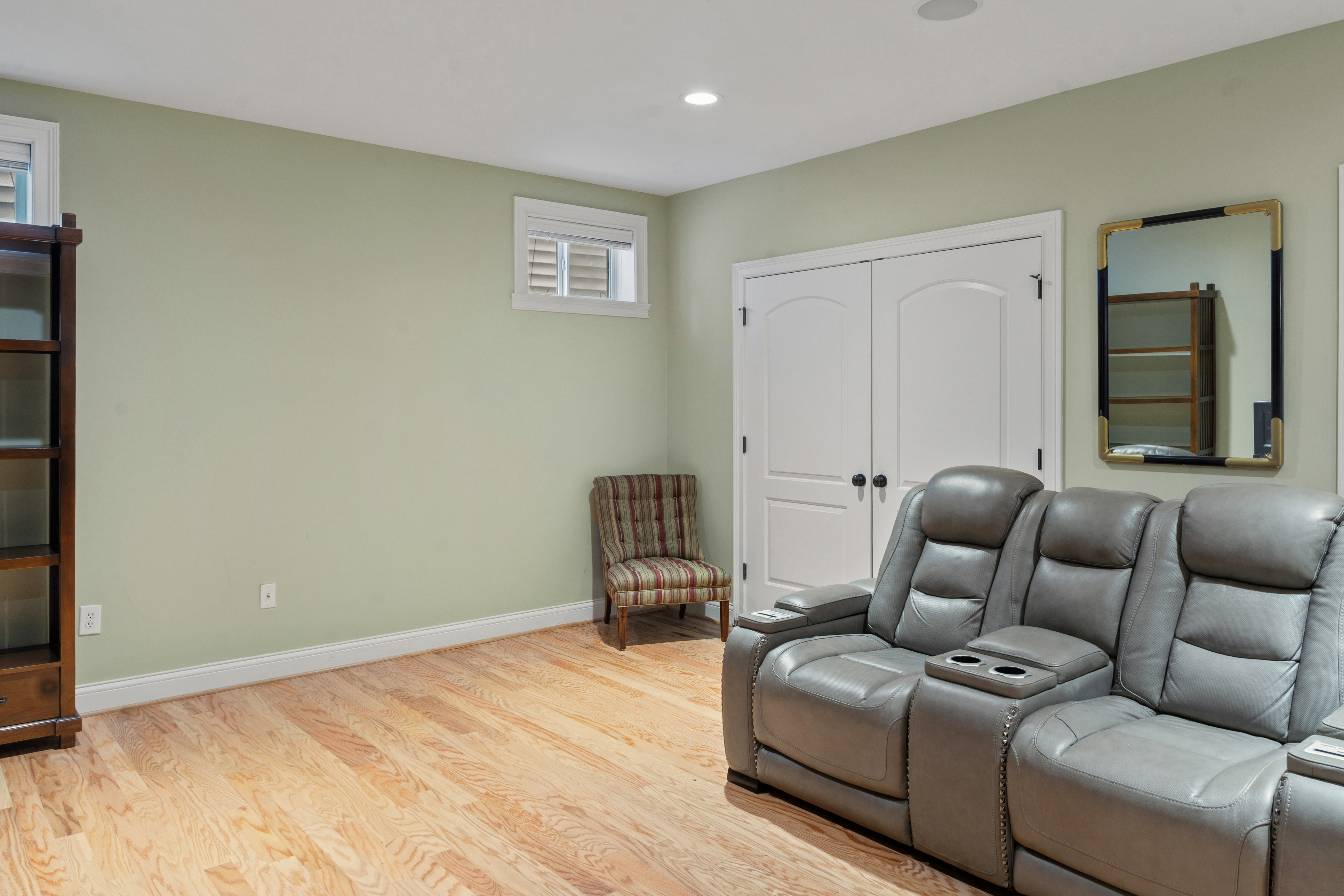 Lower level alternate angle showing leather recliner seating, closet, and egress windows