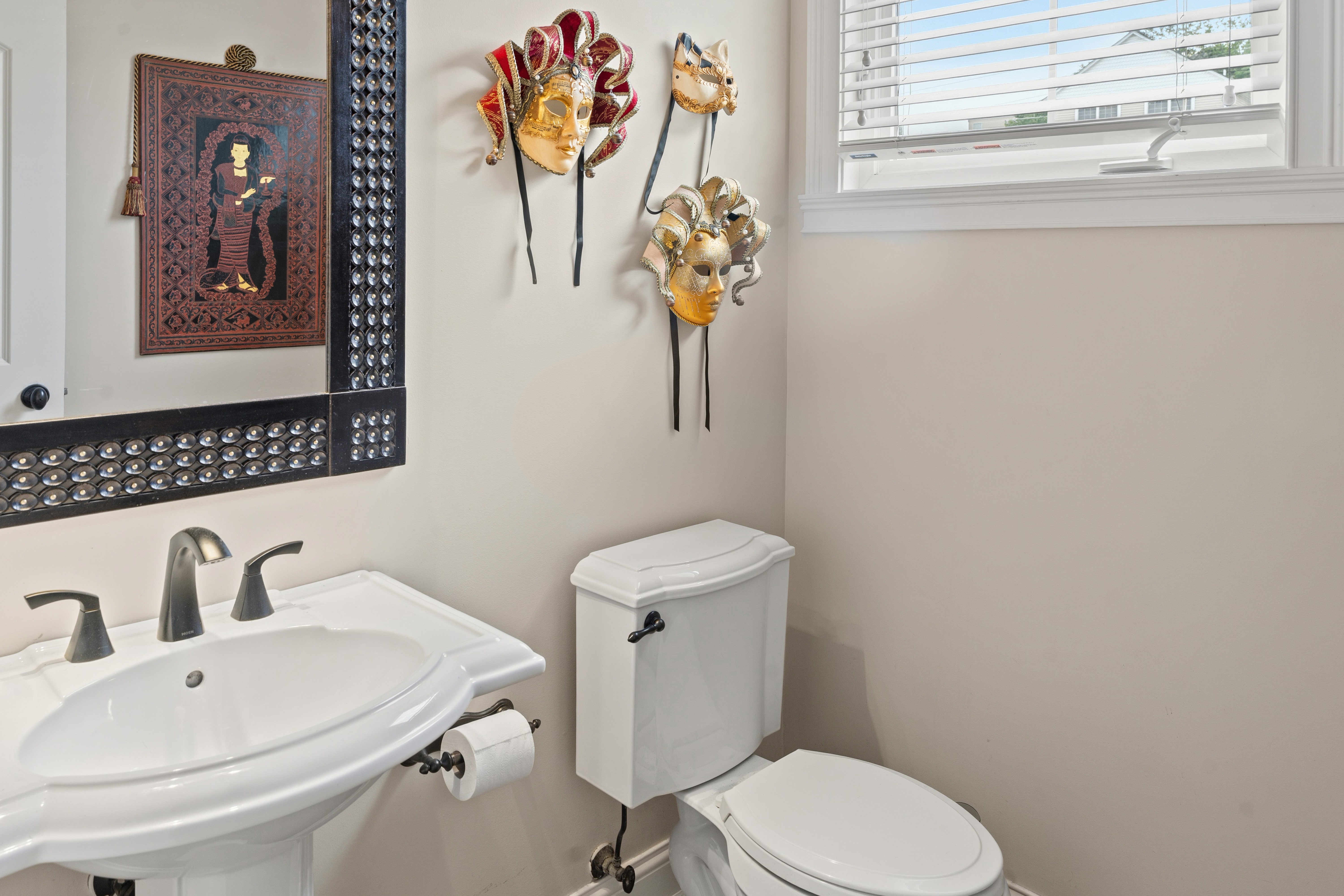 Powder room with pedestal sink, ornate mirror, and decorative wall art