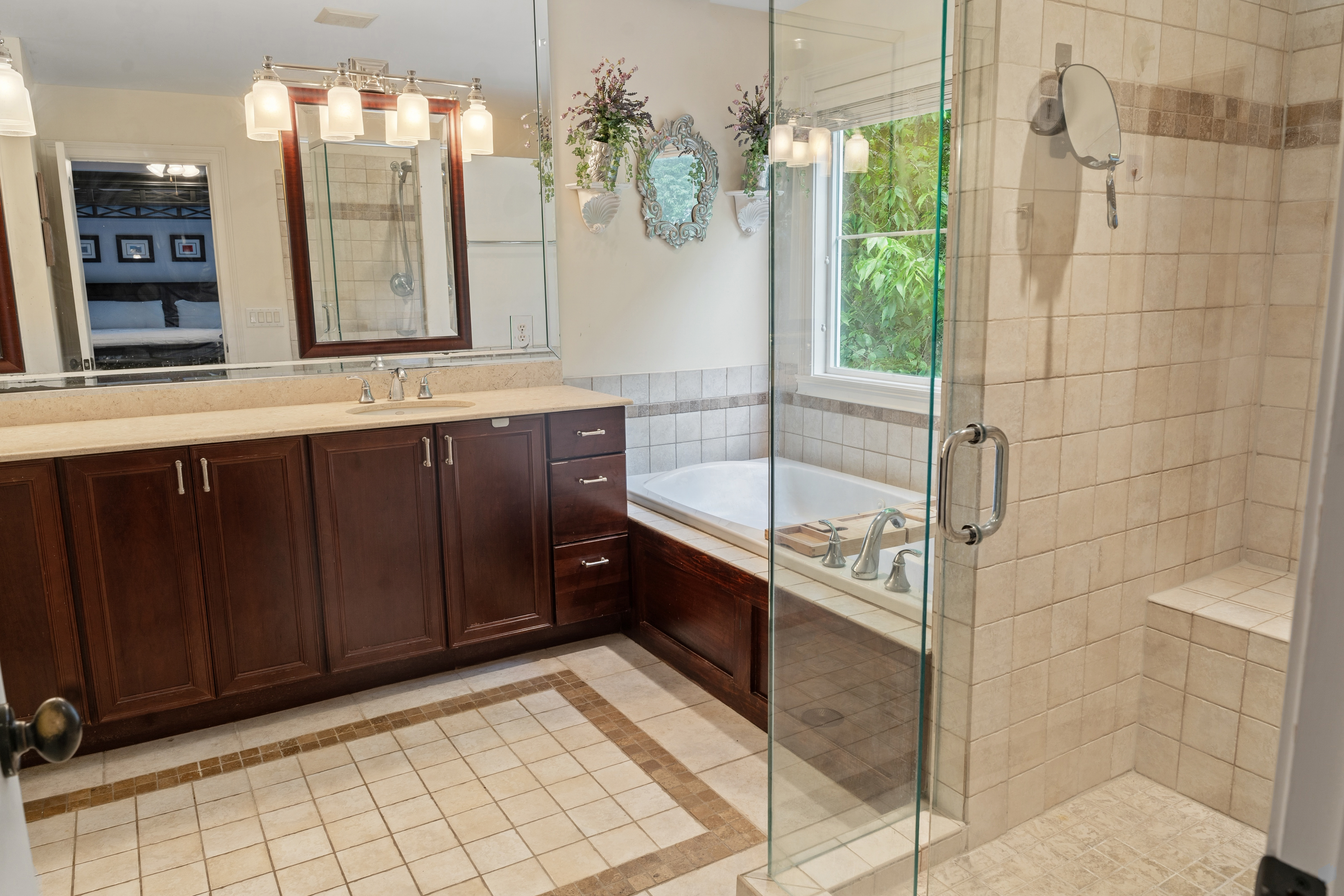 Primary bathroom with double vanity, soaking tub, frameless glass shower, and tile flooring