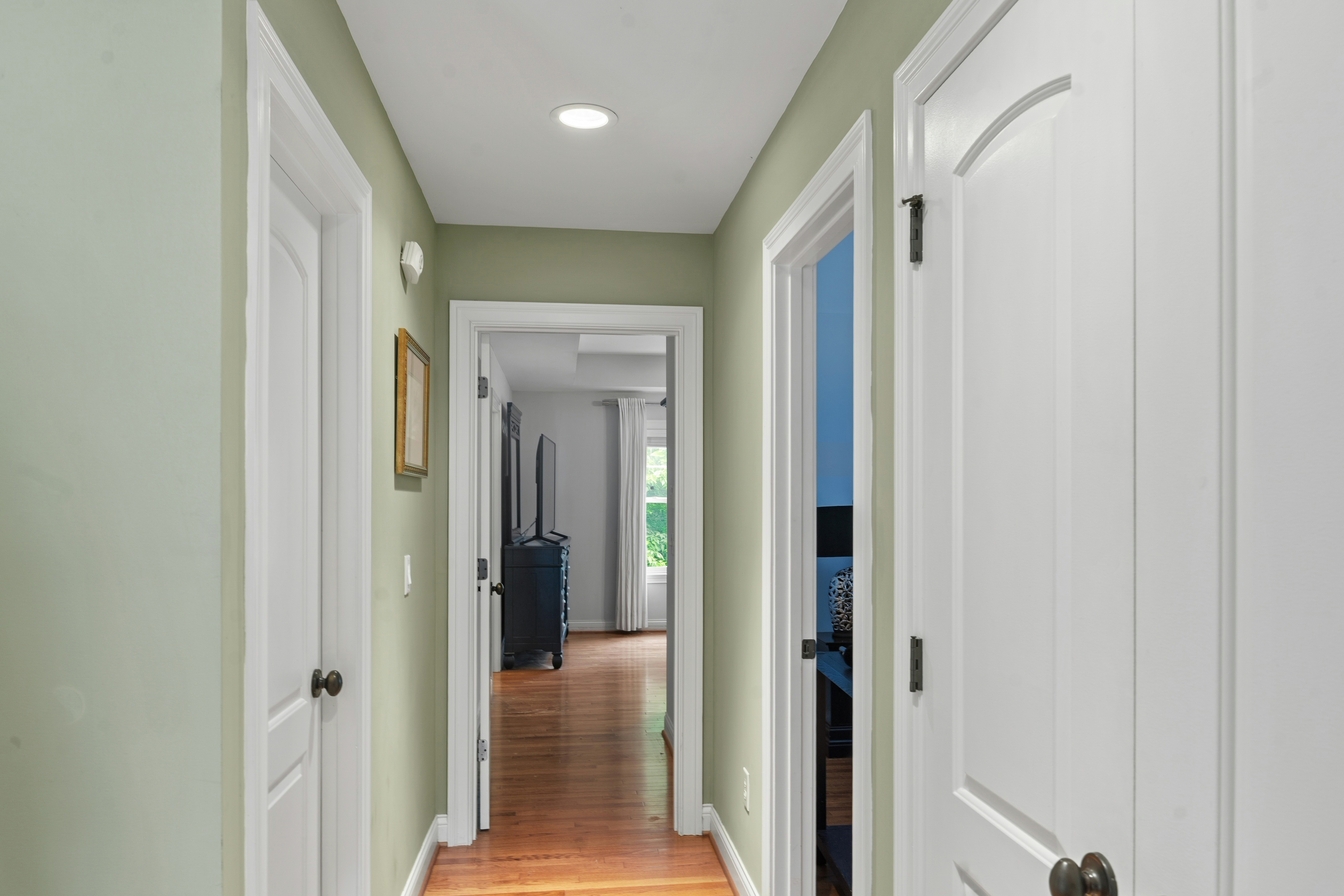 Upper hallway with multiple bedroom doors, hardwood floors, and recessed lighting