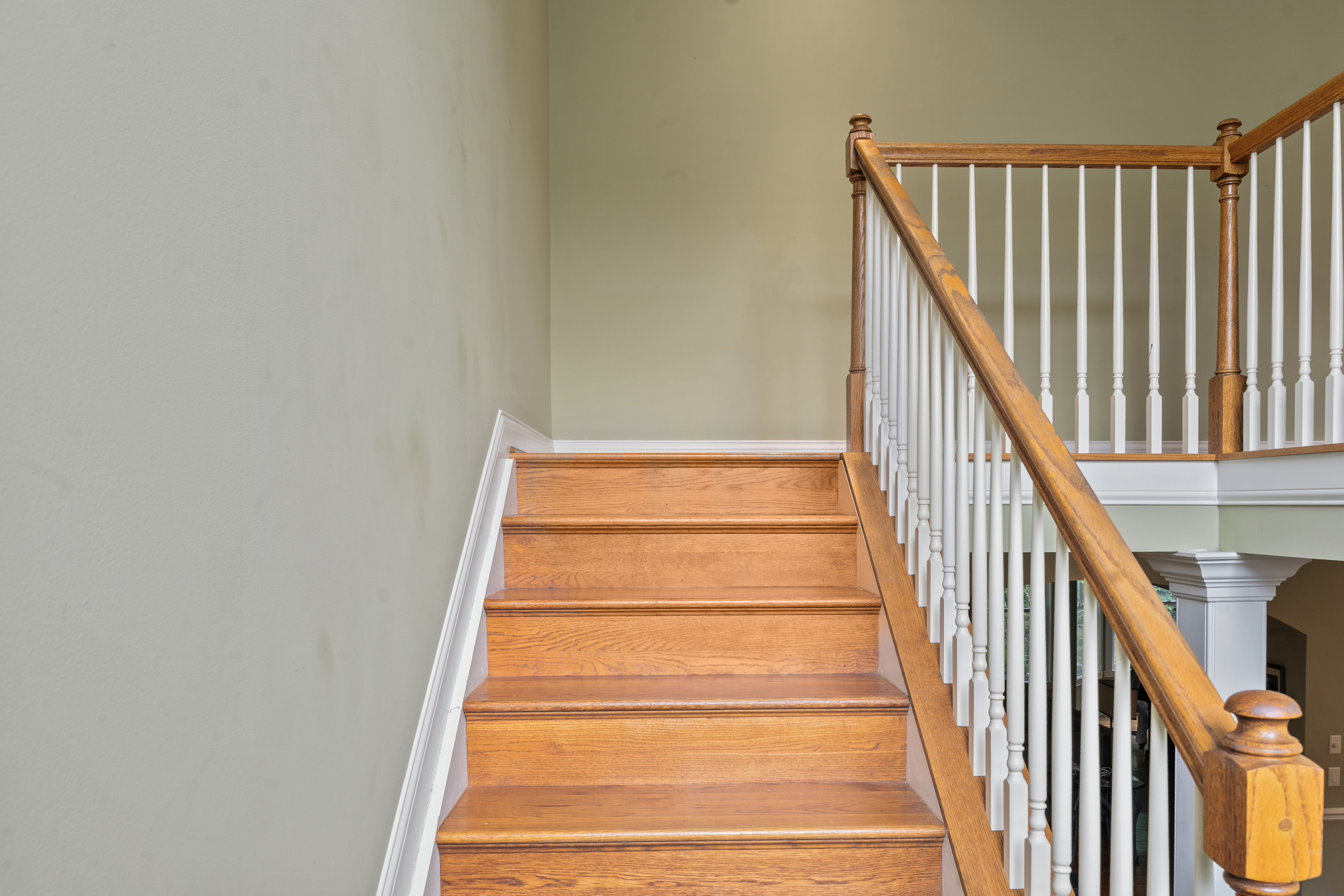 Upper floor landing with wood staircase, white balusters, and open hallway view