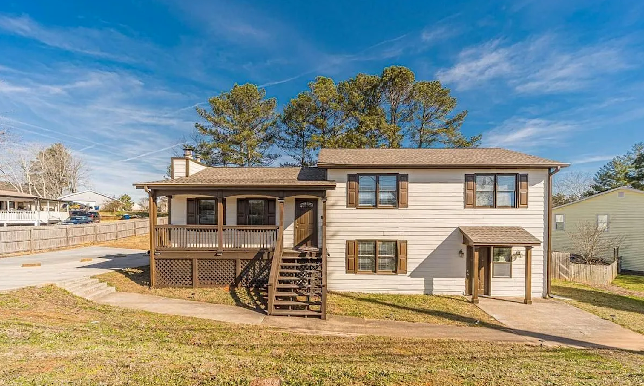 Alternate front exterior photo of the split-level property with porch and blue sky